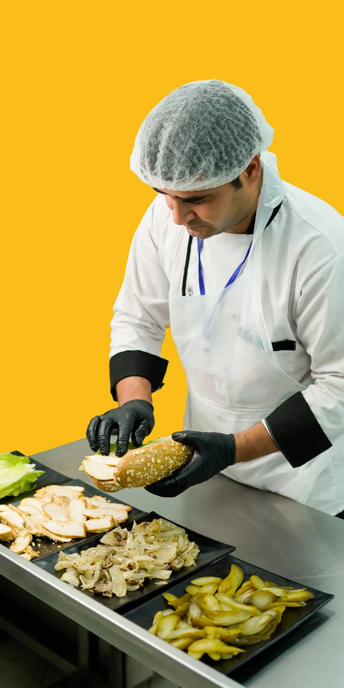 A Kurda kitchen team member wearing gloves and a hair covering while preparing sandwiches